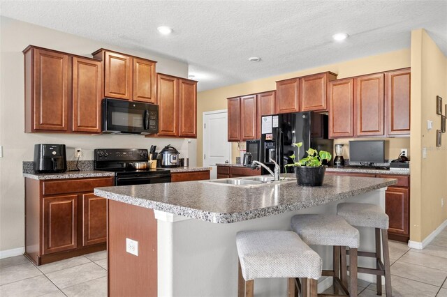 6708 Hazelnut Spice Dr, Ruskin, FL 33573 - kitchen with a sink, an island with sink, light tile patterned floors, and black appliances