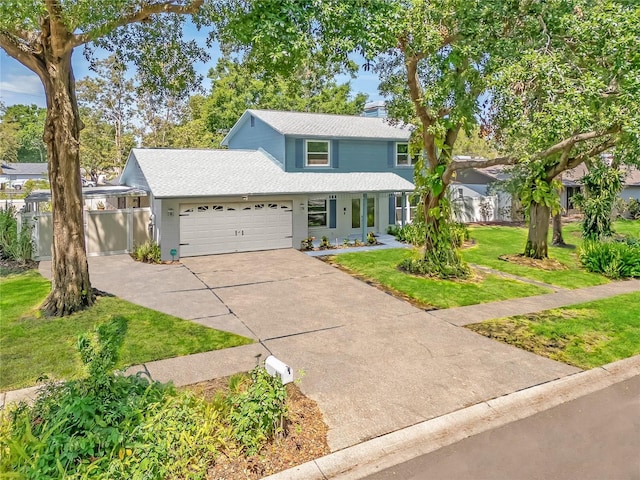traditional-style house with driveway, roof with shingles, fence, a front lawn, and an attached garage