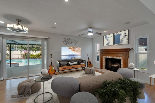 living room featuring wood finished floors, a fireplace, baseboards, ceiling fan, and recessed lighting