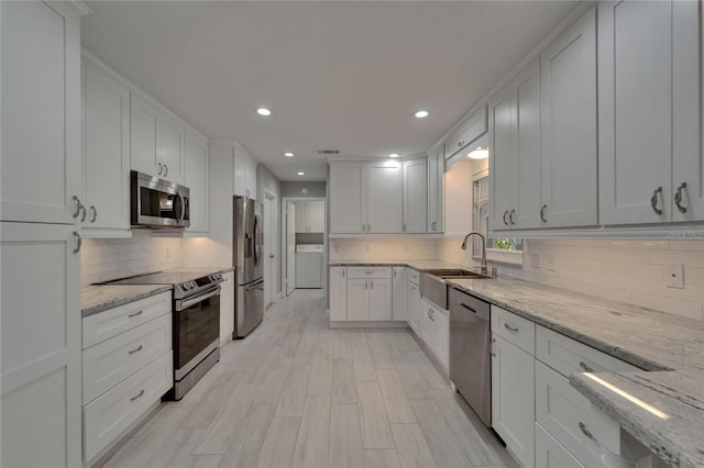 kitchen featuring white cabinets, appliances with stainless steel finishes, a sink, recessed lighting, and tasteful backsplash