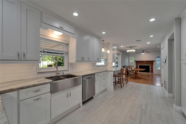 kitchen featuring a sink, decorative backsplash, a fireplace, and dishwasher