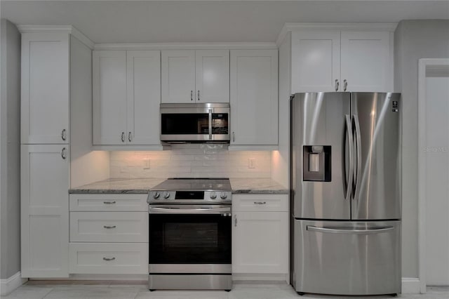 kitchen featuring white cabinets, appliances with stainless steel finishes, decorative backsplash, and light stone counters
