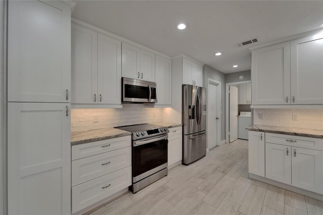 kitchen with visible vents, washer / clothes dryer, white cabinets, tasteful backsplash, and appliances with stainless steel finishes