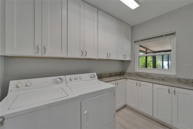 washroom featuring light wood finished floors, cabinet space, and washer and clothes dryer