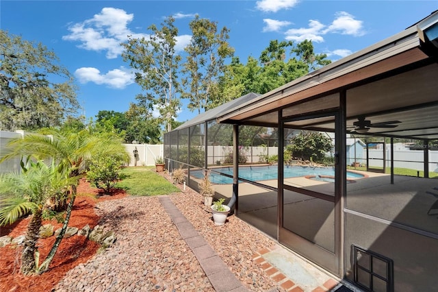 exterior space featuring a fenced backyard, a fenced in pool, ceiling fan, and glass enclosure