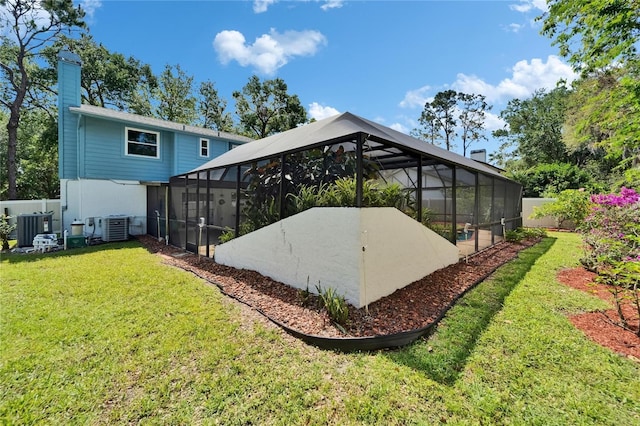 back of property with central air condition unit, a lawn, fence, and glass enclosure