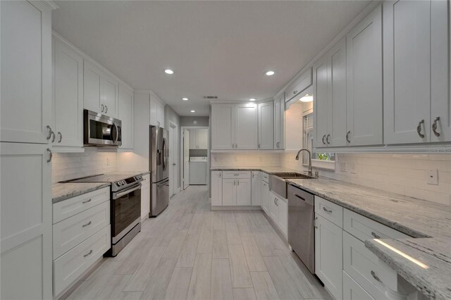 9410 Alanbrooke St, Temple Terrace, FL 33637 - kitchen with stainless steel appliances, washer / dryer, tasteful backsplash, white cabinetry, and recessed lighting