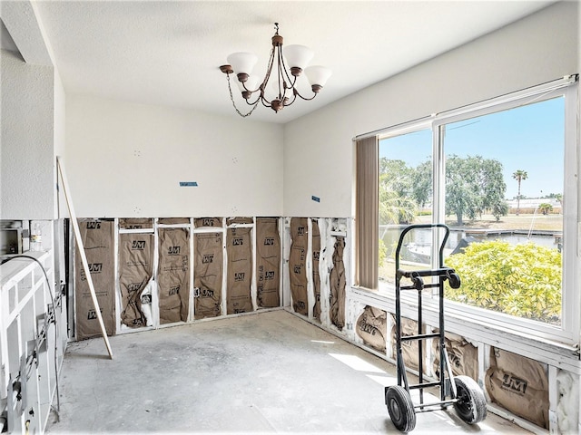 interior space featuring a notable chandelier and unfinished concrete flooring