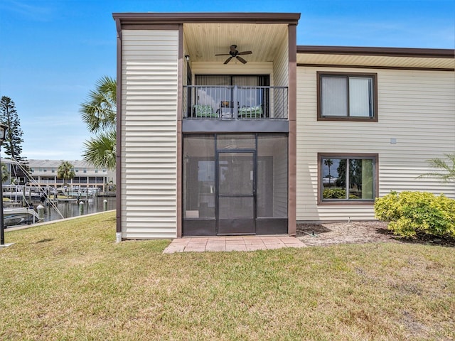 back of property featuring a yard, a water view, ceiling fan, and a balcony