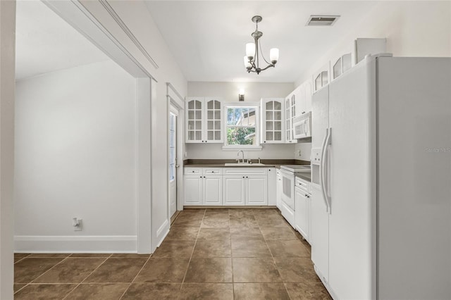906 E Broad St, Tampa, FL 33604 - kitchen featuring white appliances, dark countertops, a chandelier, white cabinets, and glass insert cabinets
