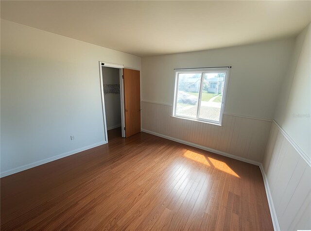 2435 37th Ave N, Saint Petersburg, FL 33713 - unfurnished bedroom with wainscoting, wood finished floors, a closet, a spacious closet, and baseboards