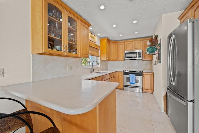 3021 Alton Dr, St Pete Beach, FL 33706 - kitchen with stainless steel appliances, a sink, a peninsula, light countertops, and tasteful backsplash