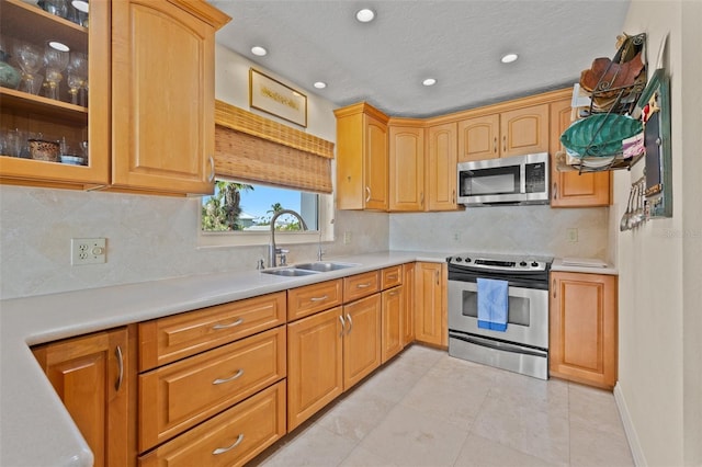 3021 Alton Dr, St Pete Beach, FL 33706 - kitchen featuring stainless steel appliances, a sink, glass insert cabinets, light countertops, and recessed lighting