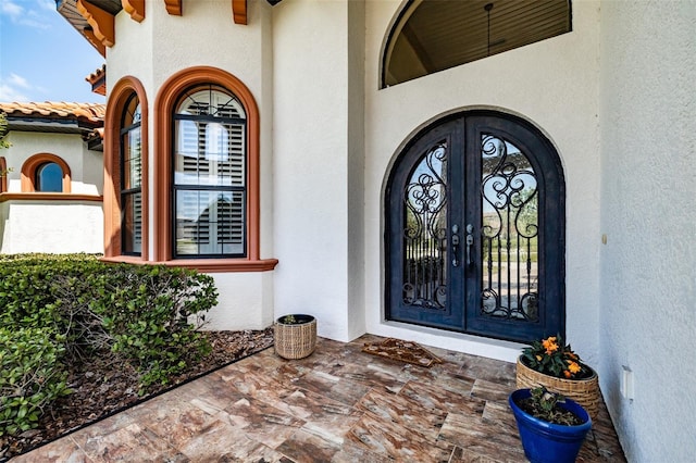 property entrance with stucco siding and french doors