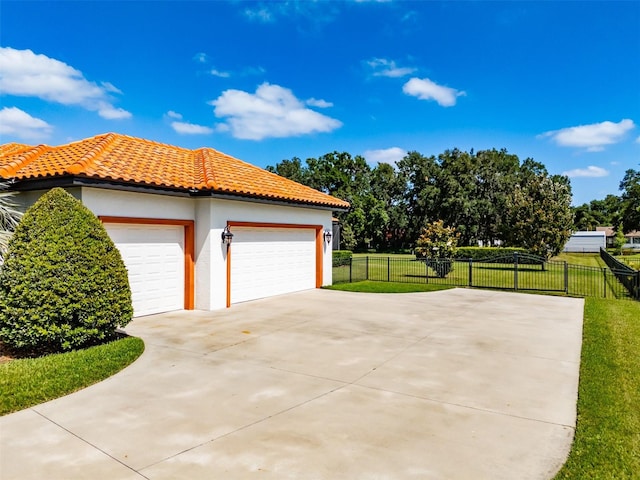 view of property exterior featuring a lawn, stucco siding, driveway, and fence