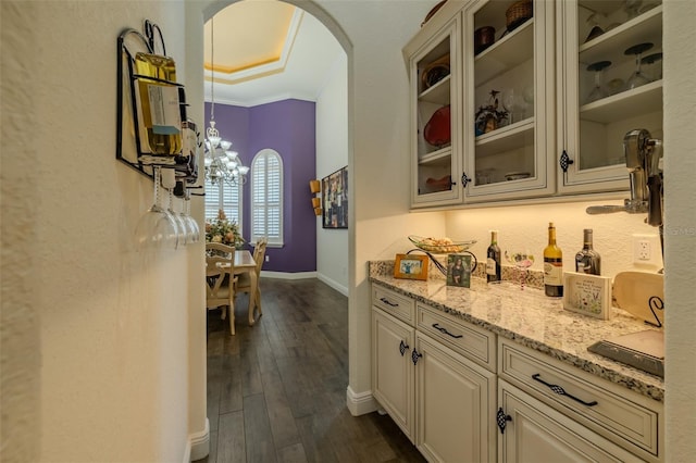 bar with arched walkways, a chandelier, ornamental molding, baseboards, and dark wood-style floors