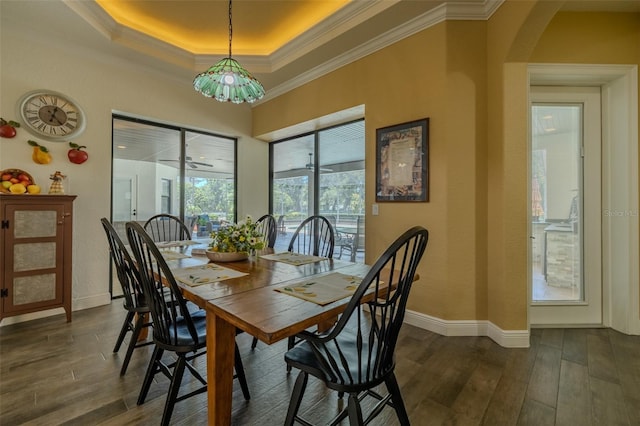 dining area with arched walkways, dark wood-style flooring, a tray ceiling, and ornamental molding