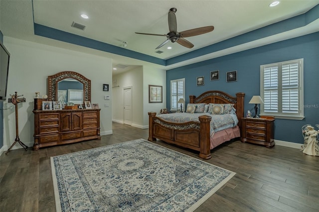 bedroom featuring visible vents, a raised ceiling, baseboards, and dark wood-style floors