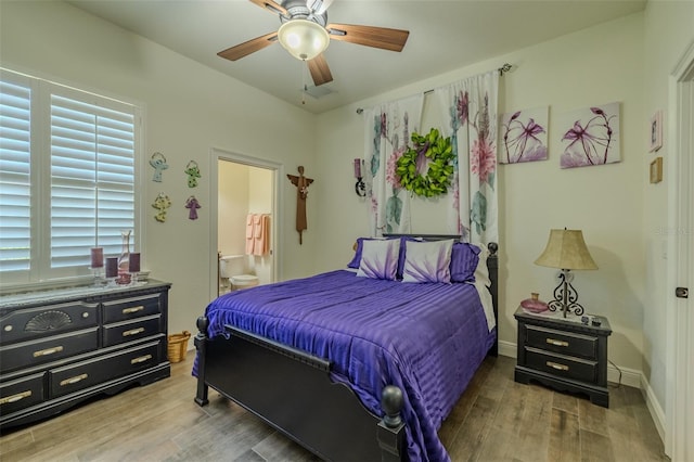 bedroom featuring visible vents, wood finished floors, baseboards, a ceiling fan, and ensuite bath