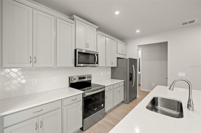 20423 Symphony Pl, Venice, FL 34293 - kitchen featuring appliances with stainless steel finishes, a sink, tasteful backsplash, recessed lighting, and light wood-style floors