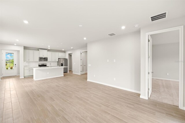 20423 Symphony Pl, Venice, FL 34293 - unfurnished living room with baseboards, recessed lighting, and light wood-style flooring