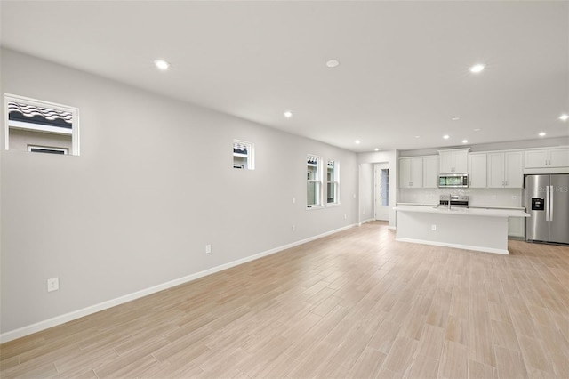 20423 Symphony Pl, Venice, FL 34293 - unfurnished living room featuring recessed lighting, light wood-style flooring, and baseboards