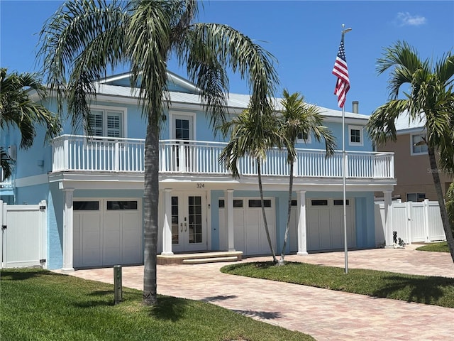 324 6th Ave, Indian Rocks Beach, FL 33785 - view of front of house featuring french doors, a gate, a garage, decorative driveway, and fence