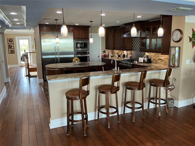 324 6th Ave, Indian Rocks Beach, FL 33785 - kitchen featuring built in appliances, baseboards, tasteful backsplash, visible vents, and dark wood-style floors