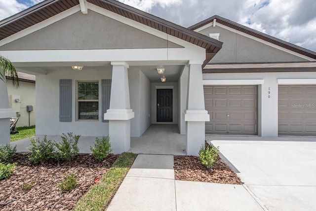 view of front of home featuring an attached garage, covered porch, stucco siding, and concrete driveway