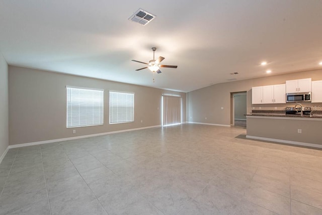 unfurnished living room with a sink, baseboards, a ceiling fan, and visible vents