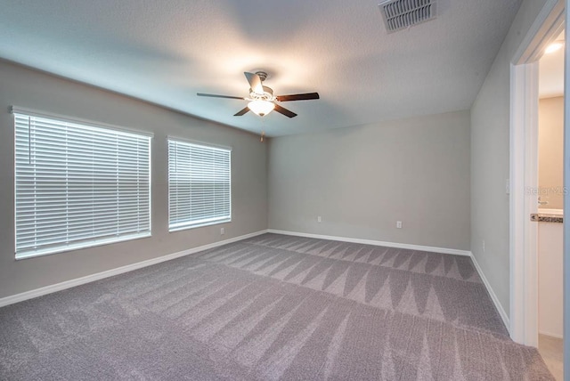 empty room with visible vents, carpet flooring, baseboards, and ceiling fan