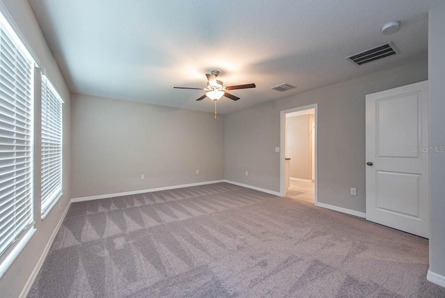 unfurnished bedroom featuring baseboards, carpet, a ceiling fan, and visible vents