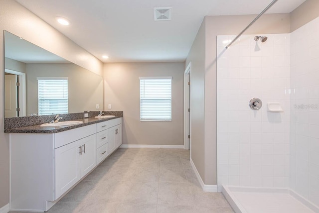 bathroom with visible vents, a sink, plenty of natural light, and a tile shower