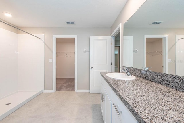 bathroom with visible vents, baseboards, vanity, and a shower stall