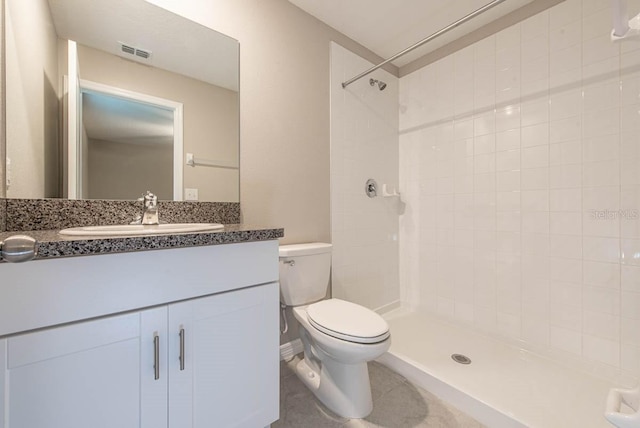 bathroom with toilet, visible vents, tiled shower, and vanity
