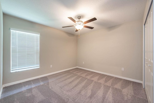 unfurnished room with carpet floors, ceiling fan, baseboards, and a textured ceiling