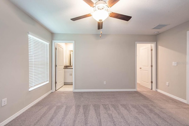 unfurnished bedroom with connected bathroom, carpet floors, a ceiling fan, baseboards, and visible vents