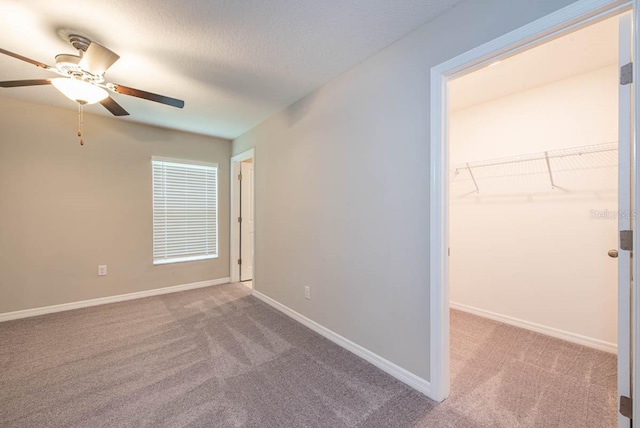 unfurnished bedroom featuring a walk in closet, baseboards, carpet, and a closet