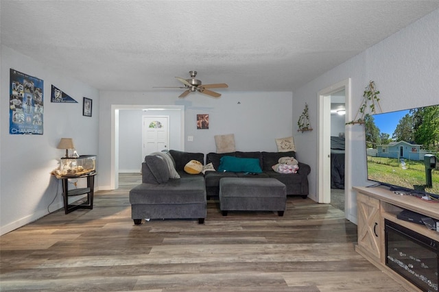 living area featuring a textured ceiling, ceiling fan, and wood finished floors