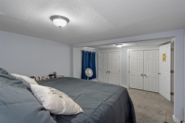 carpeted bedroom featuring a textured ceiling and multiple closets