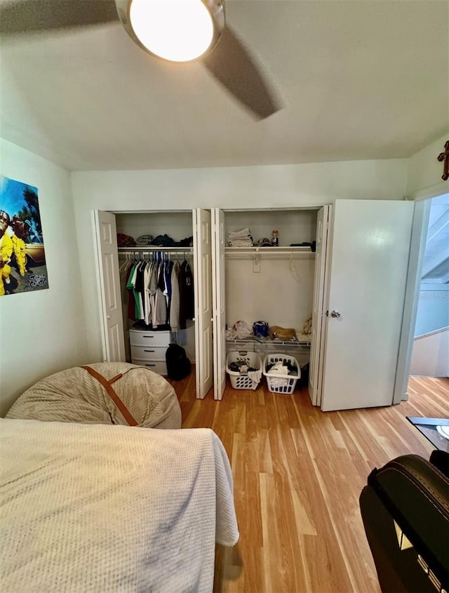 bedroom featuring light wood-style floors, a ceiling fan, and two closets