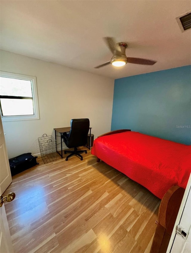 bedroom featuring a ceiling fan, visible vents, and light wood finished floors