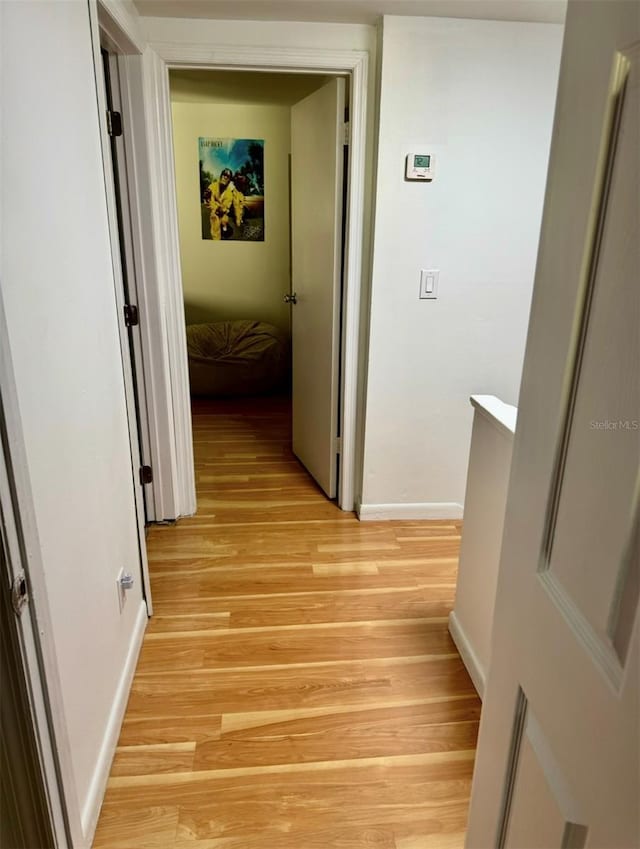 hall with baseboards and light wood-style flooring