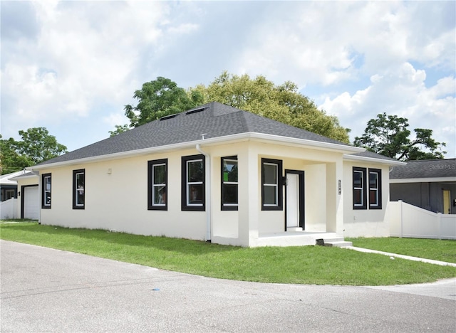 view of front of house featuring fence, an attached garage, stucco siding, a front lawn, and a shingled roof