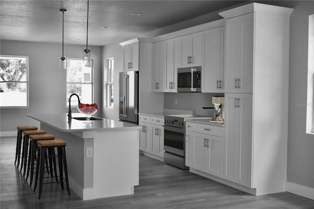 kitchen featuring a center island with sink, stainless steel appliances, light countertops, and a sink