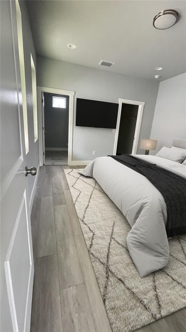 bedroom featuring baseboards, recessed lighting, visible vents, and wood finished floors