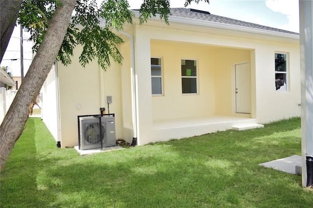 rear view of property with a lawn, stucco siding, a shingled roof, and ac unit