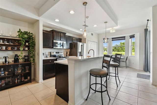 1003 Fairwaycove Ln Unit 103, Bradenton, FL 34212 - kitchen with stainless steel appliances, a kitchen breakfast bar, light tile patterned floors, a kitchen island with sink, and light countertops