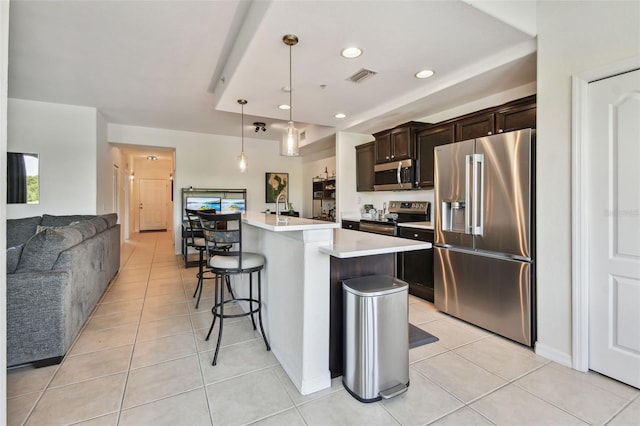 1003 Fairwaycove Ln Unit 103, Bradenton, FL 34212 - kitchen featuring appliances with stainless steel finishes, light countertops, dark brown cabinetry, a breakfast bar, and light tile patterned floors