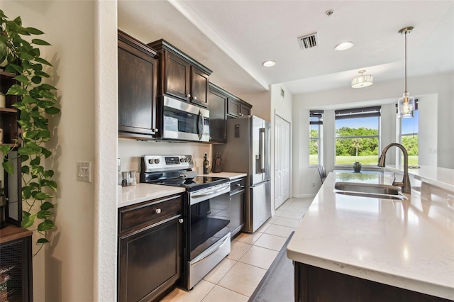 1003 Fairwaycove Ln Unit 103, Bradenton, FL 34212 - kitchen with stainless steel appliances, a sink, light tile patterned floors, dark brown cabinetry, and pendant lighting